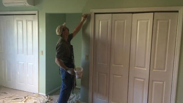 Contractor painting white trim around closet door